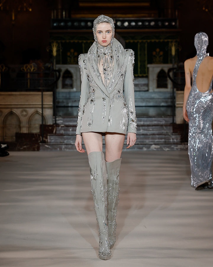Model wearing a silver blazer and boots set by Gaurav Gupta
